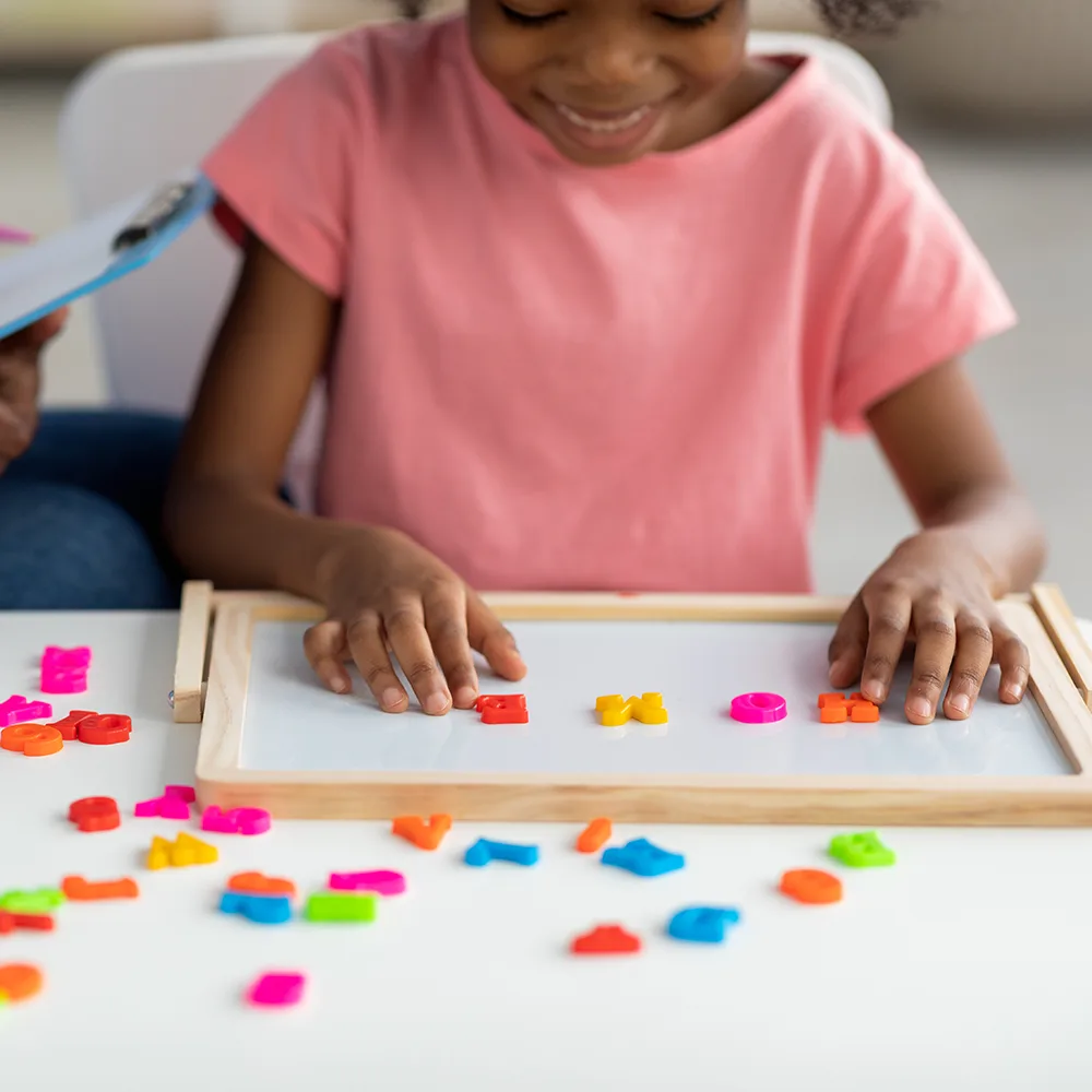A child using magnetized colorful letters to spell HOME at a Little Newtons daycare