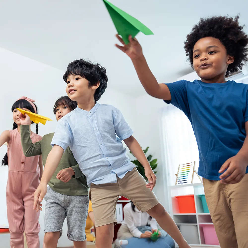 Children launching colorful paper airplanes in a Little Newtons daycare
