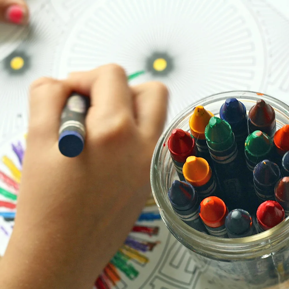 A child using a blue crayon to color a wheel at a Little Newtons daycare