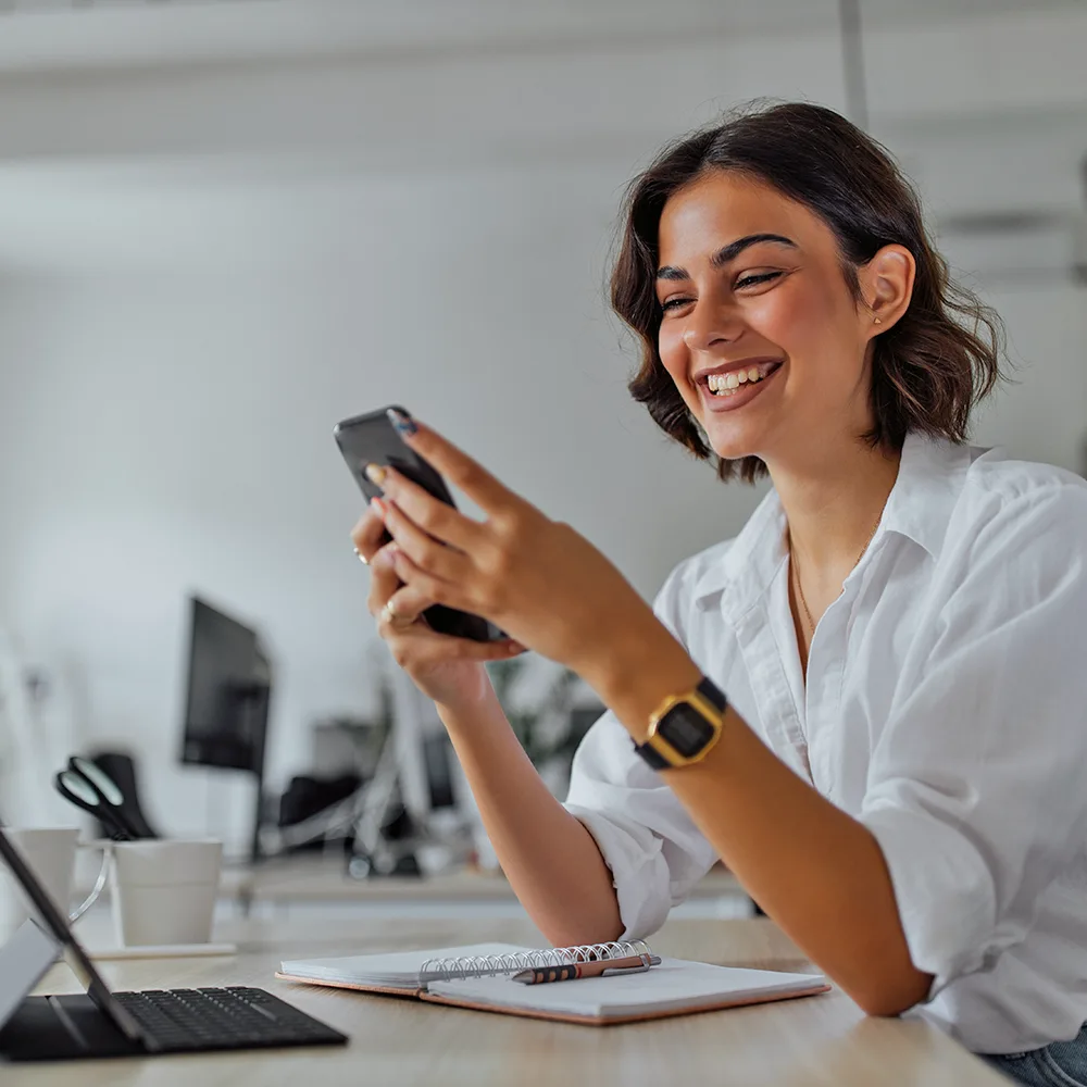A smiling adult on her phone receiving an update