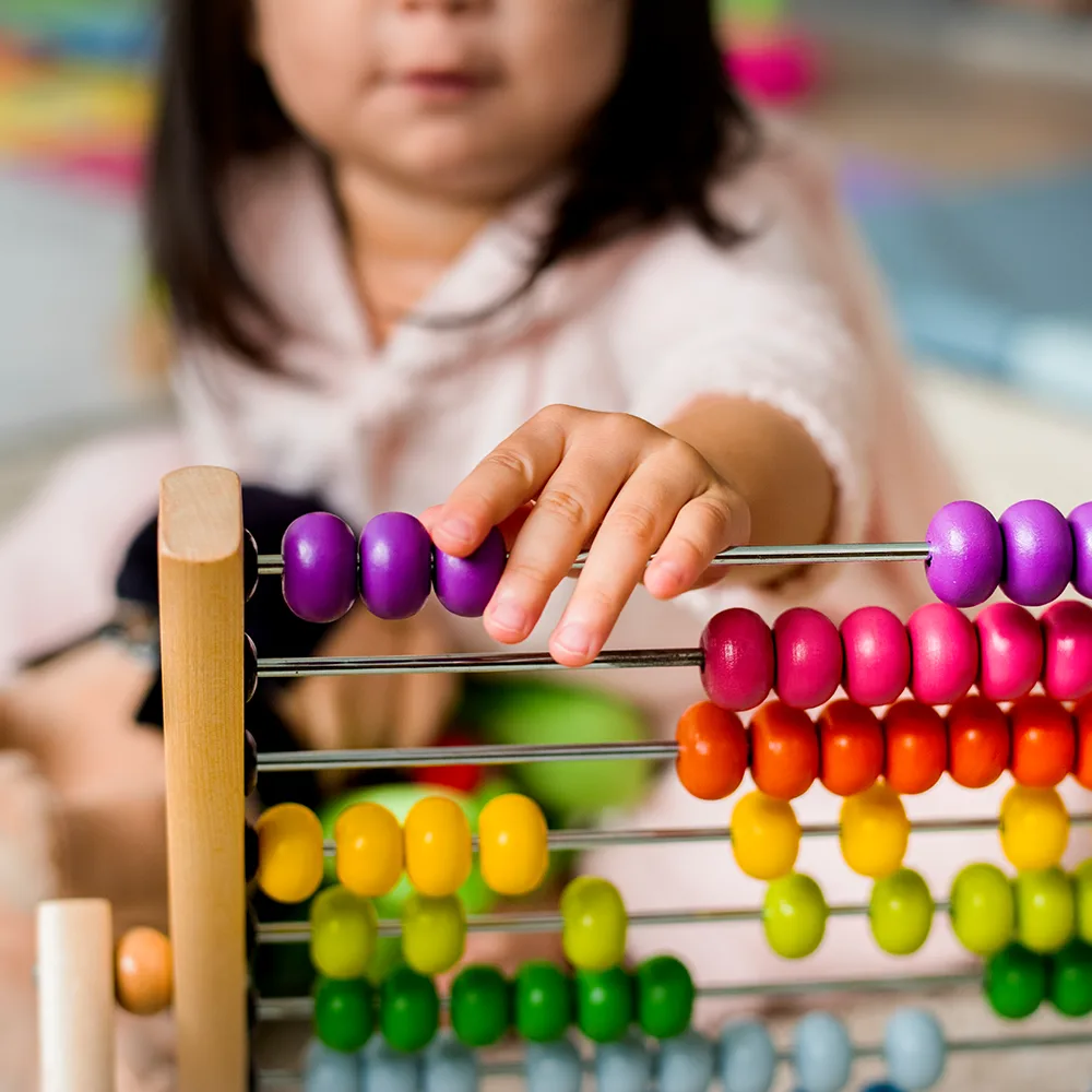 A child working with beads on an abacus at Little Newtons daycare