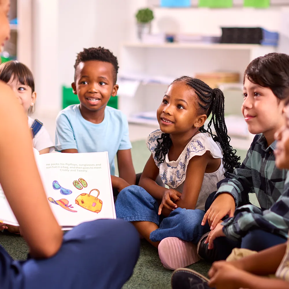 A teacher reading from a picture book to a group of children