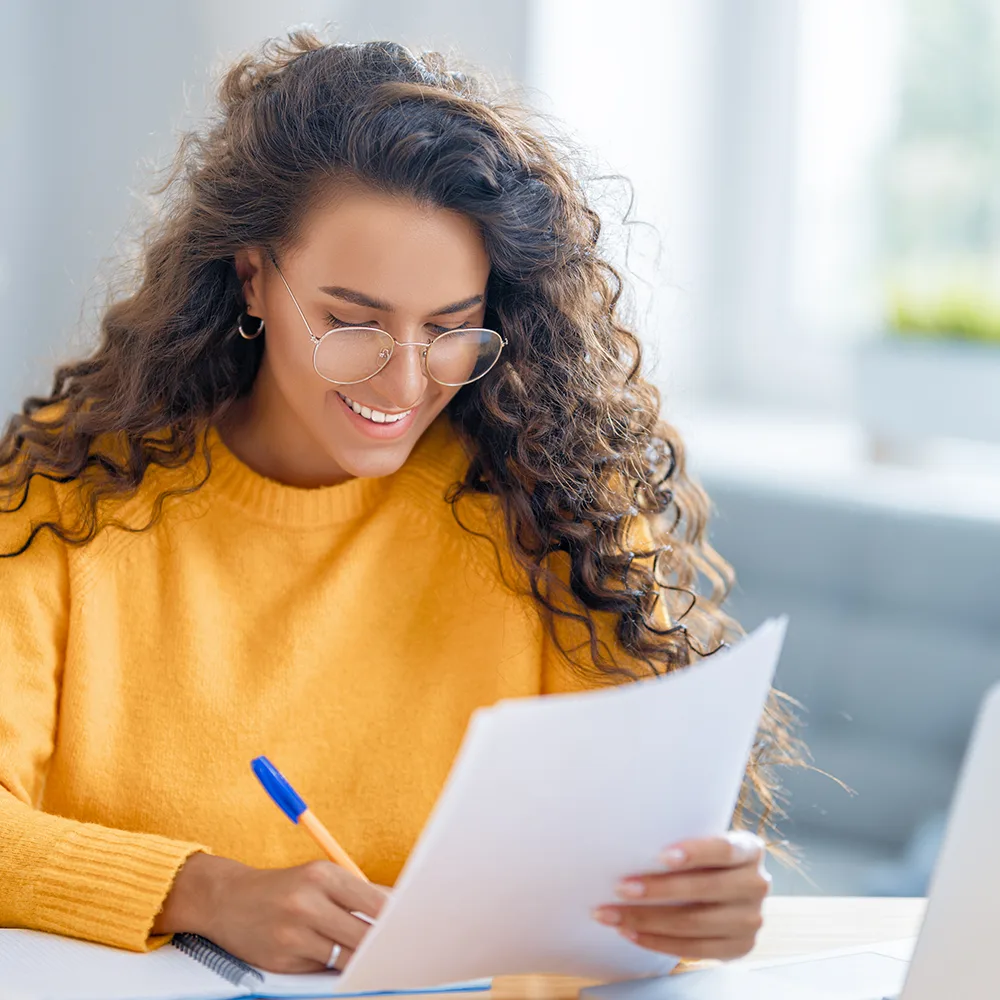 A mother with a pen looking at a registration form.