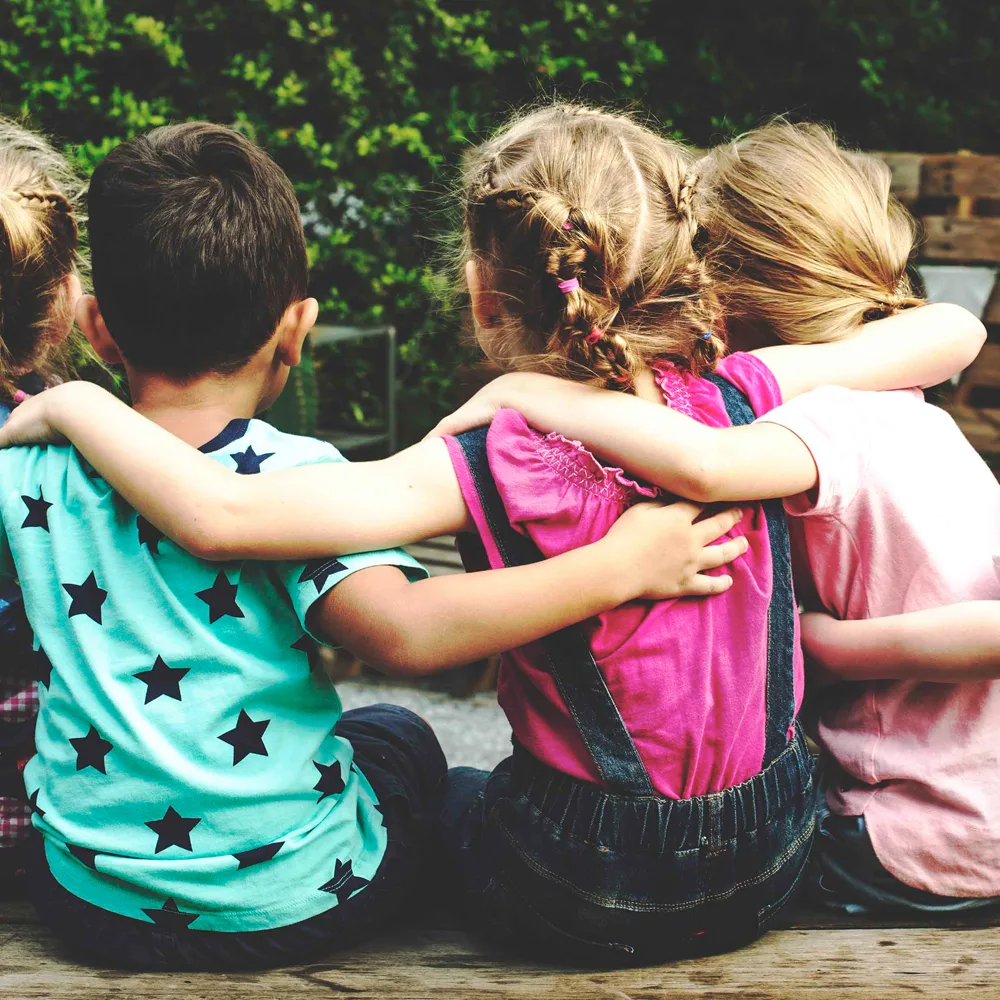 Children with their arms around each other sitting in a circle