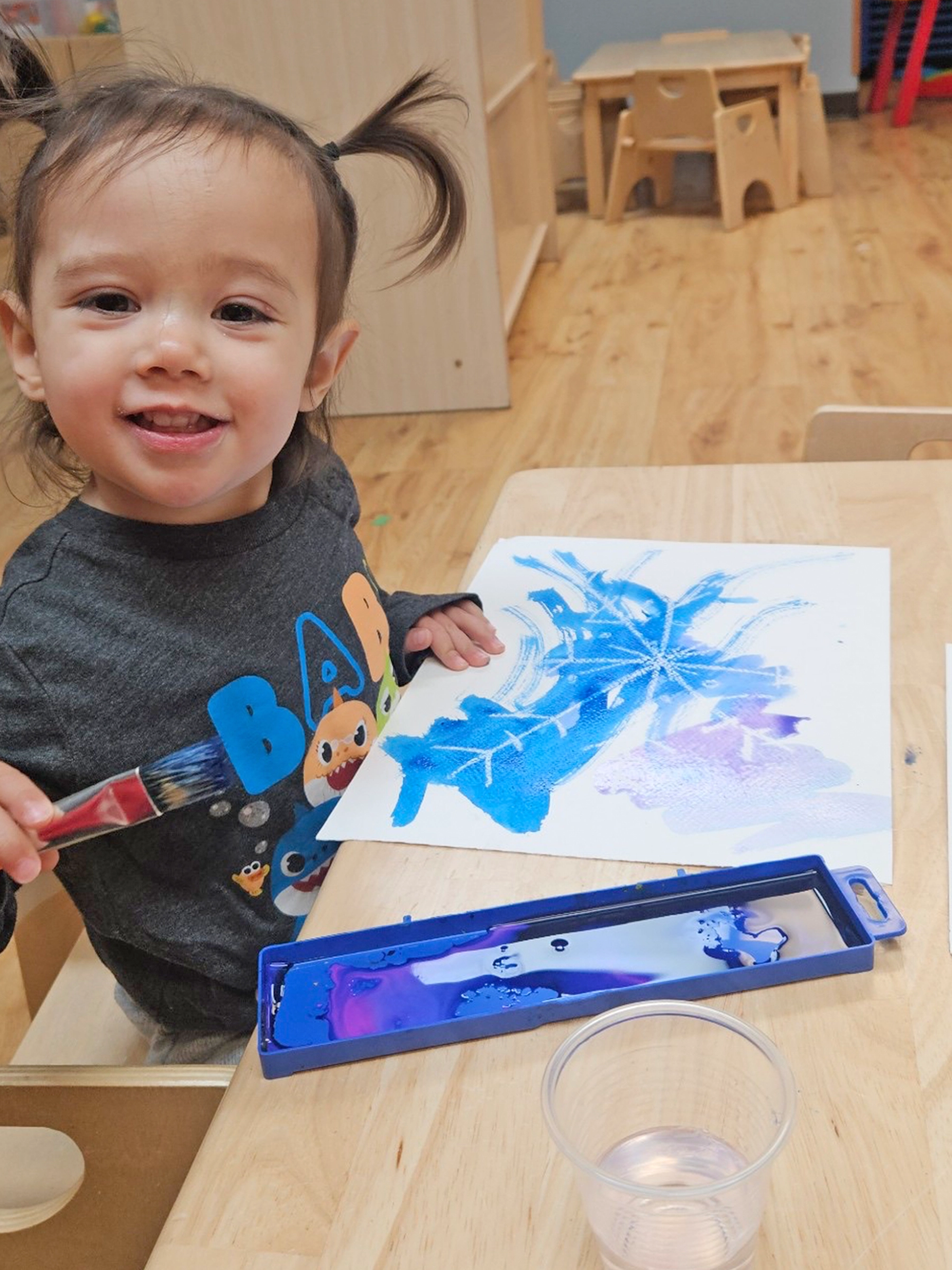 Child coloring with blue crayon at a Little Newtons daycare.