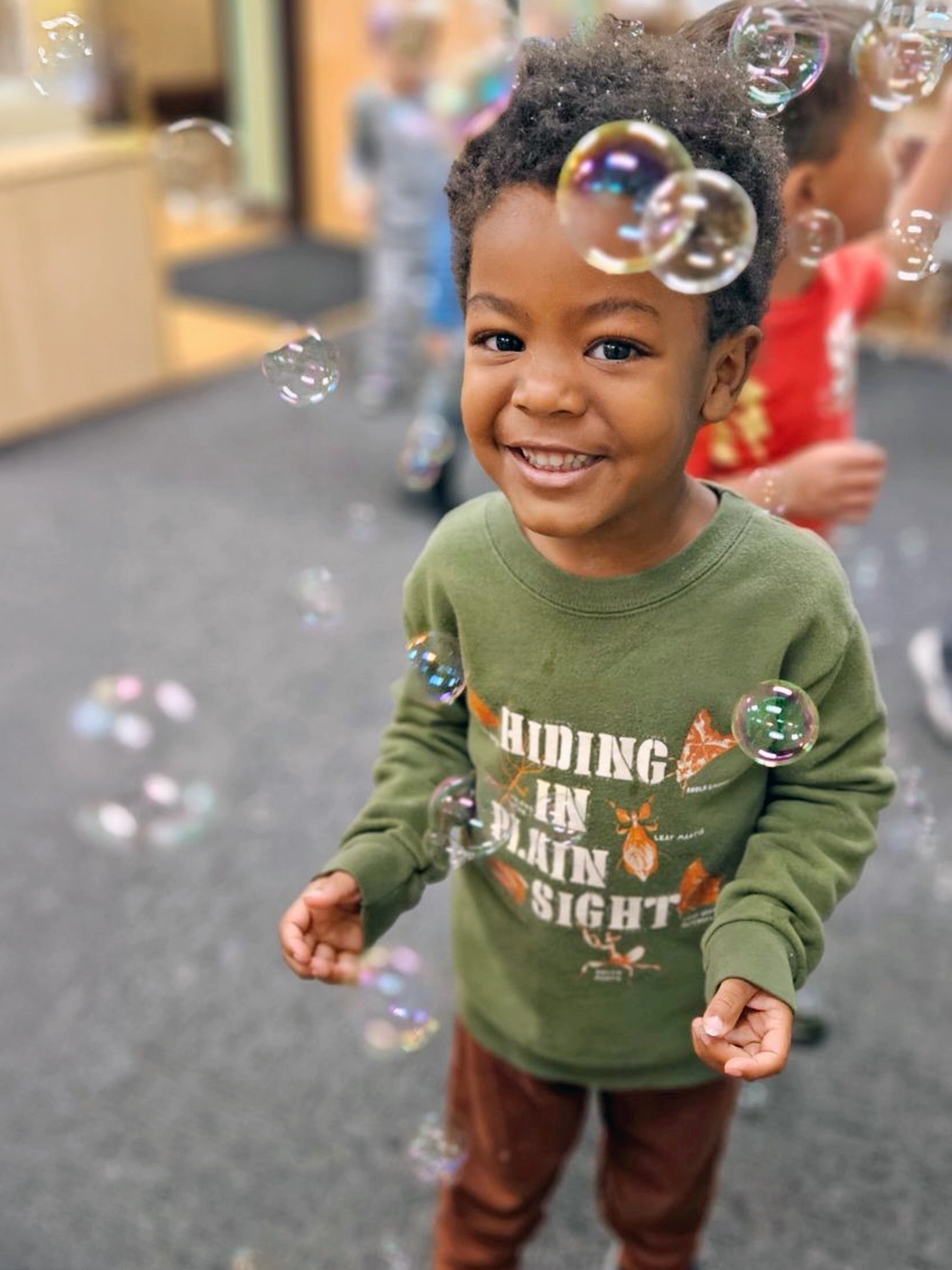 Child standing among floating bubbles at a Little Newtons daycare.