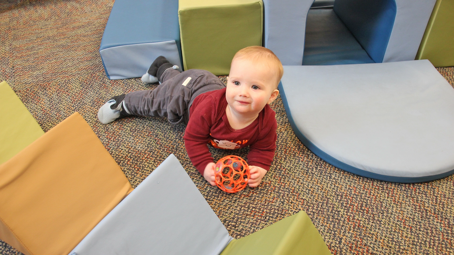 A child playing with a toy on the floor of a Little Newtons daycare