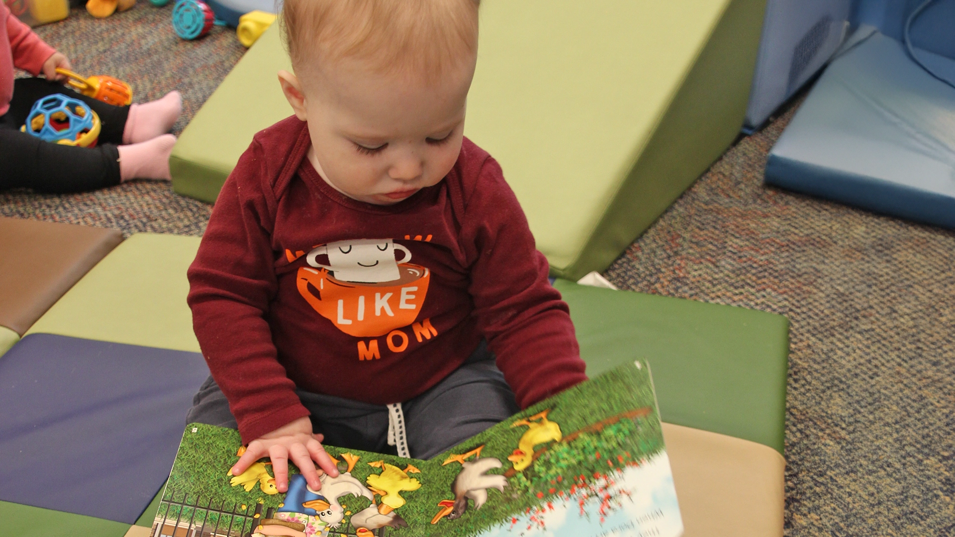 A young child looking at a picture book at a Little Newtons daycare