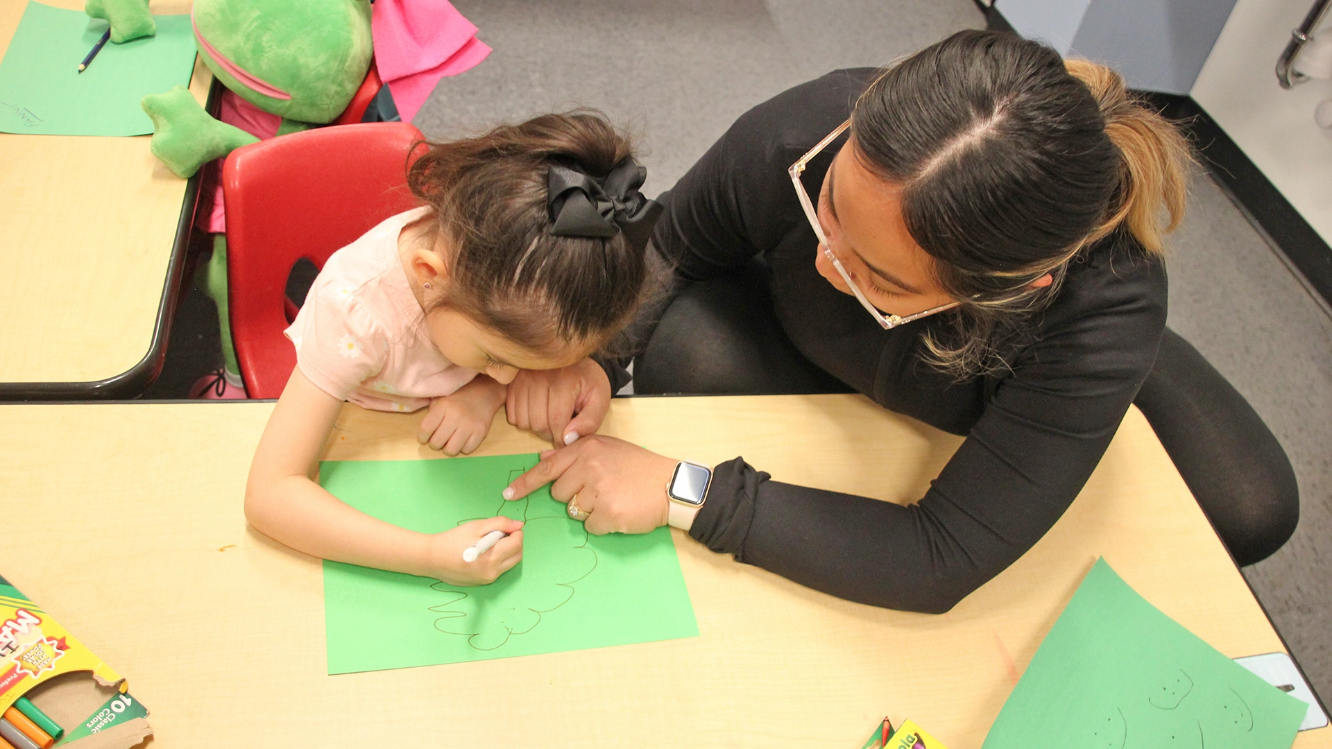 A teacher helping a child with drawing at a Little Newtons daycare