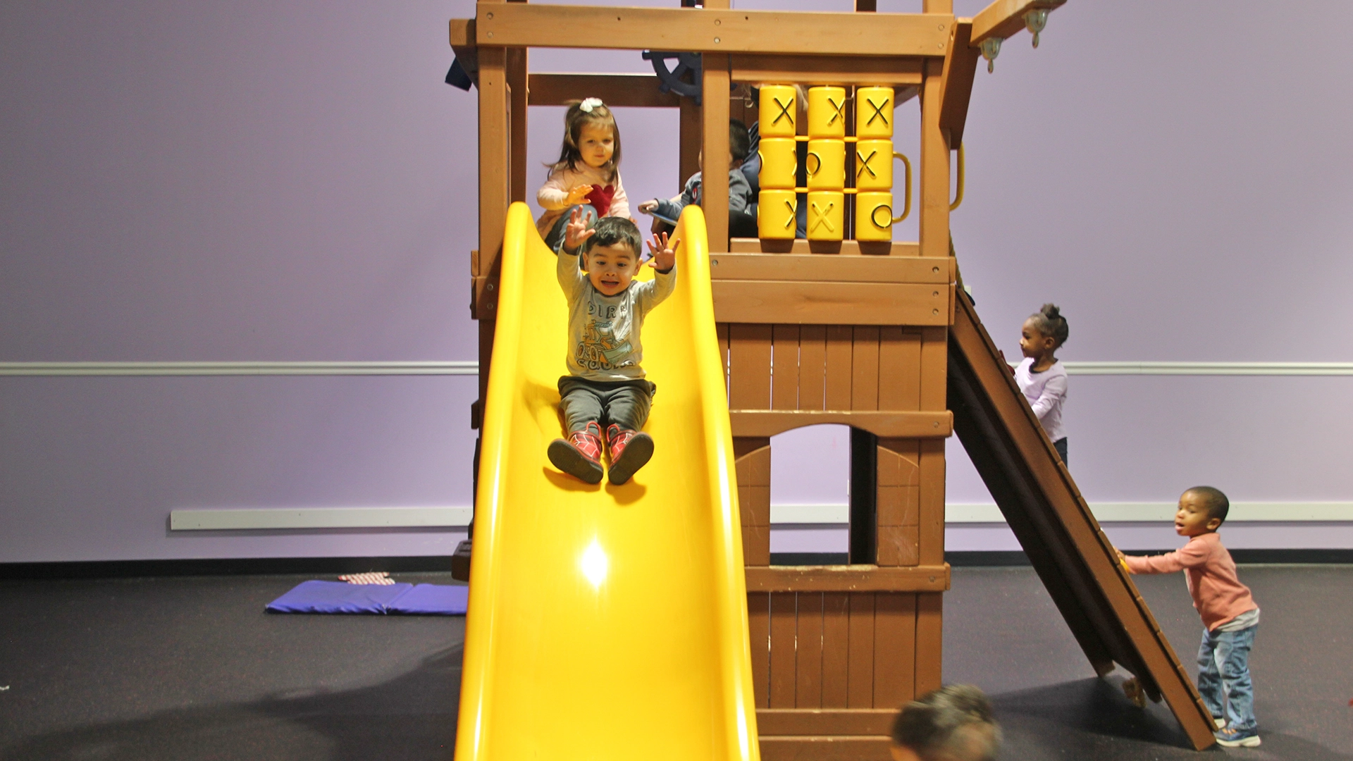 A child going down a yellow slide at a Little Newtons daycare