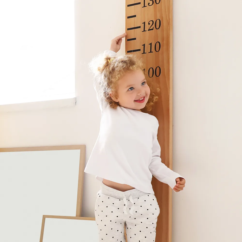 A child standing next to a large ruler measuring height