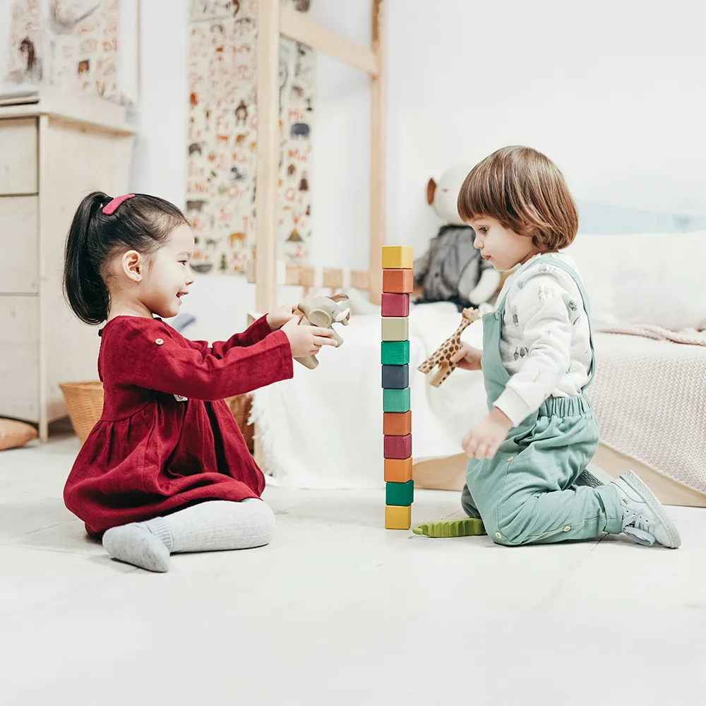 Two children stacking colorful blocks on a floor at Little Newtons daycare
