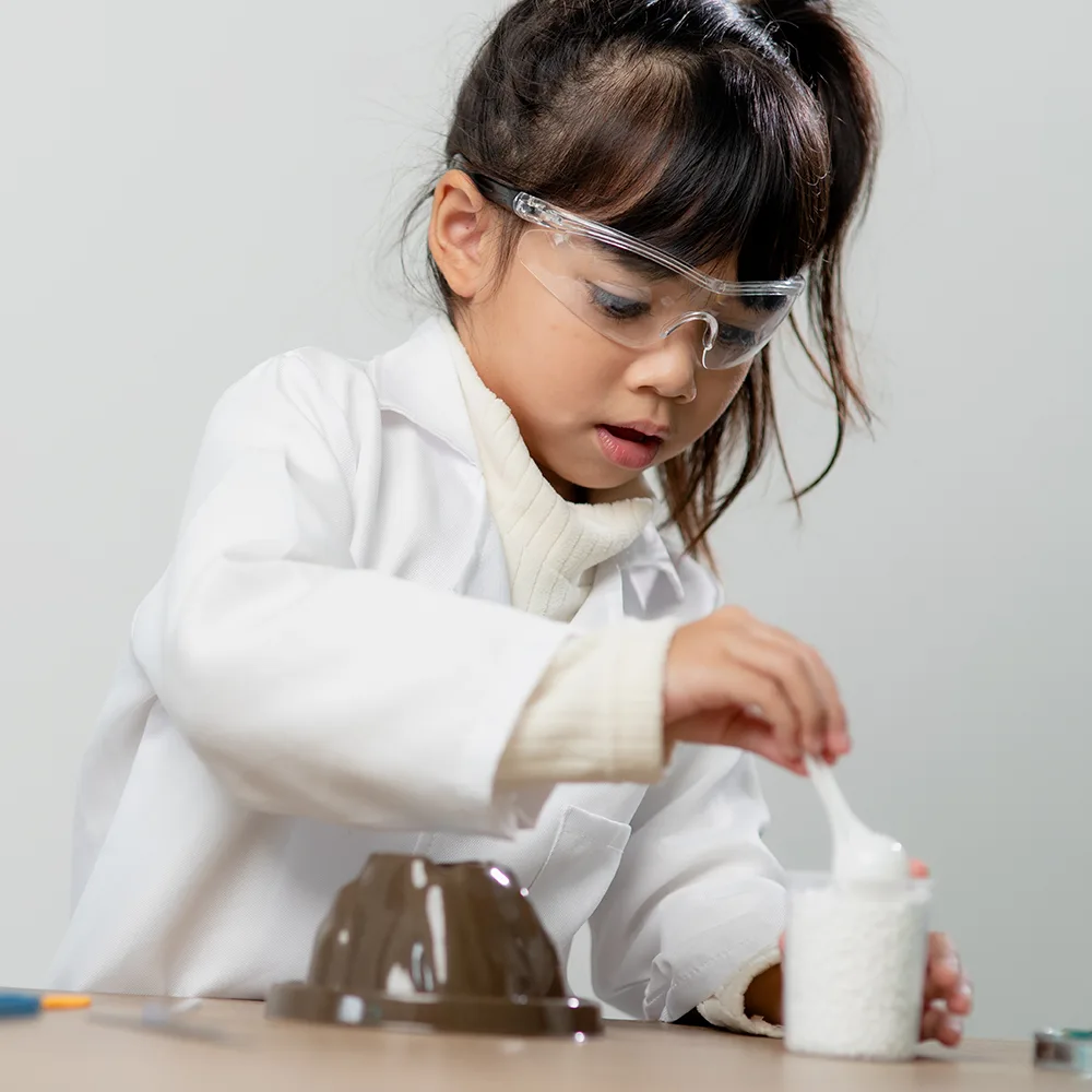 A young child using a spoon during a science experiment at Little Newtons daycare