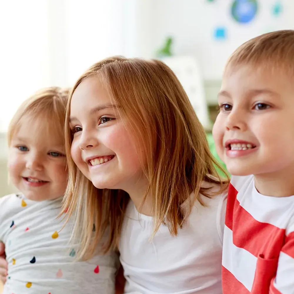 Three children hugging and smiling at a Little Newtons daycare