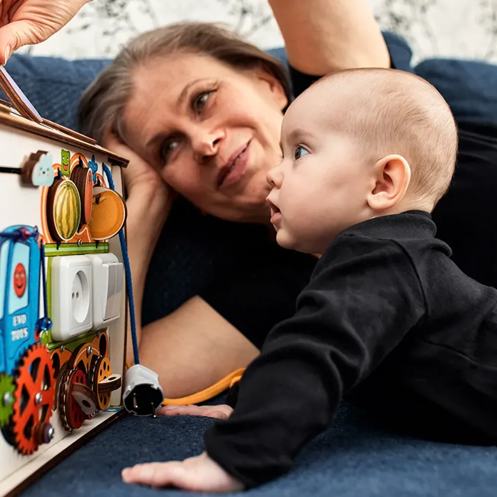 A teacher showing an infant a play box on the floor at a Little Newtons daycare