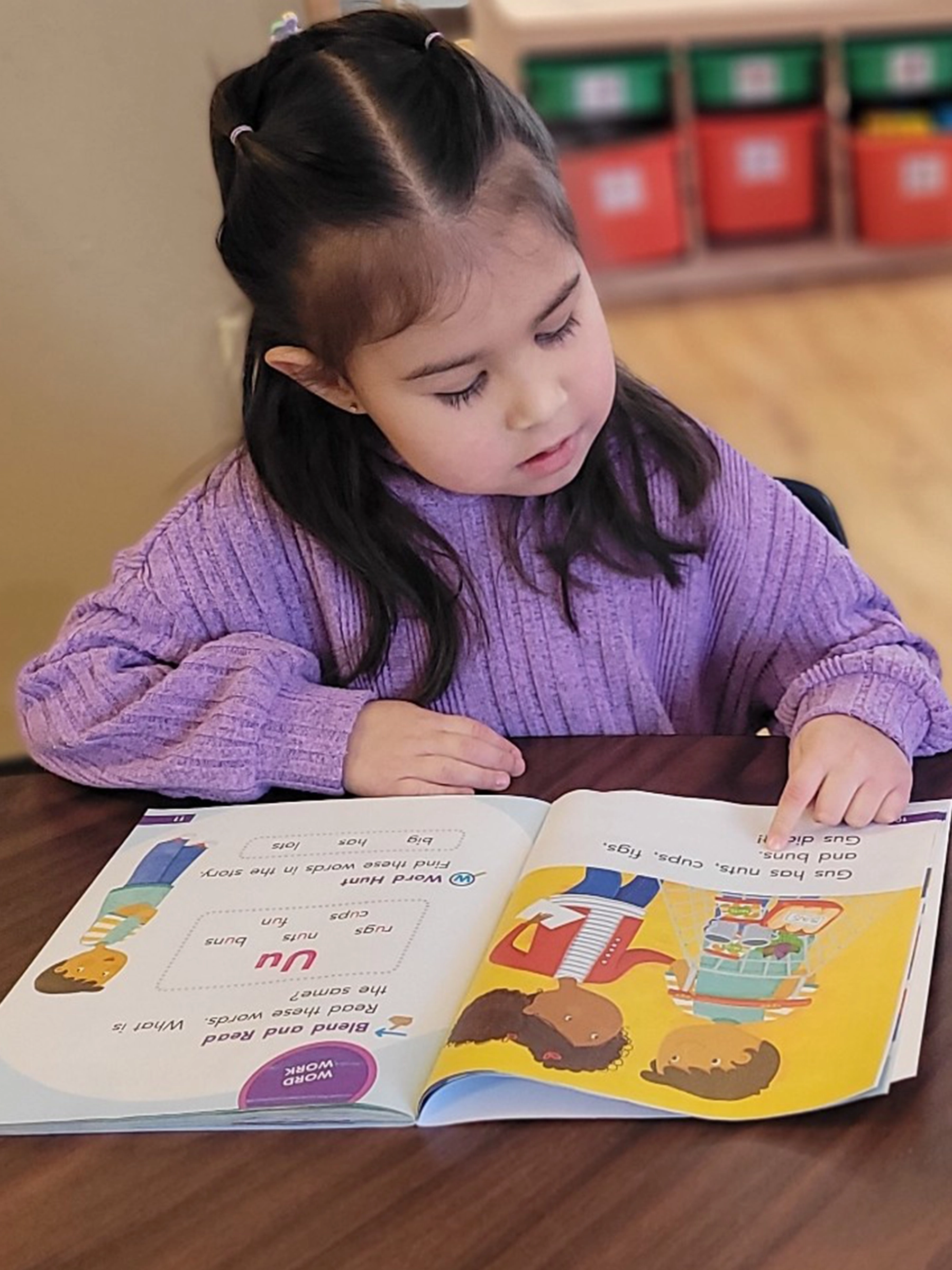 A child in purple reading a book at Little Newtons daycare.